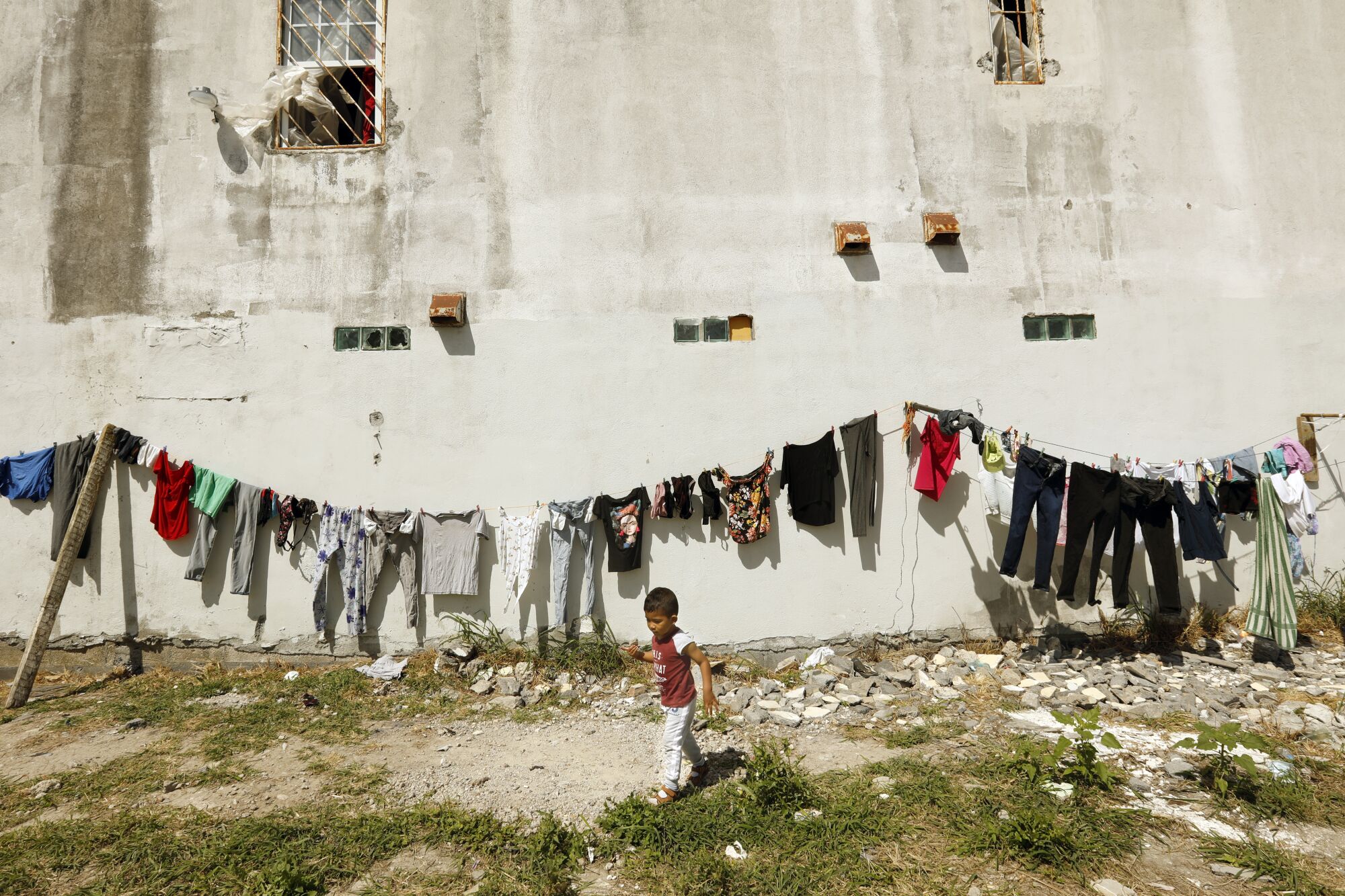 A boy walks near a line of laundry. 