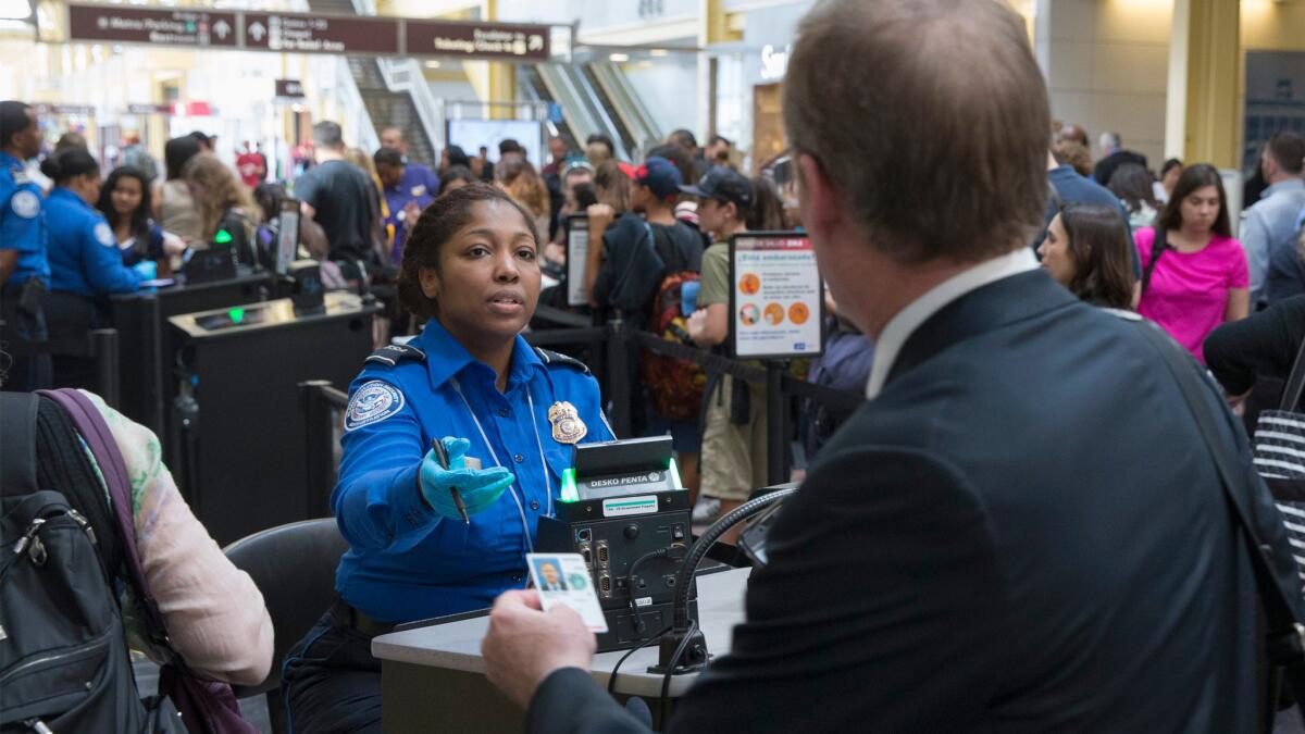 A Transportation Security Administration agent inspects travelers' documents on June 30 at Ronald Reagan Washington National Airport in Arlington, Va.