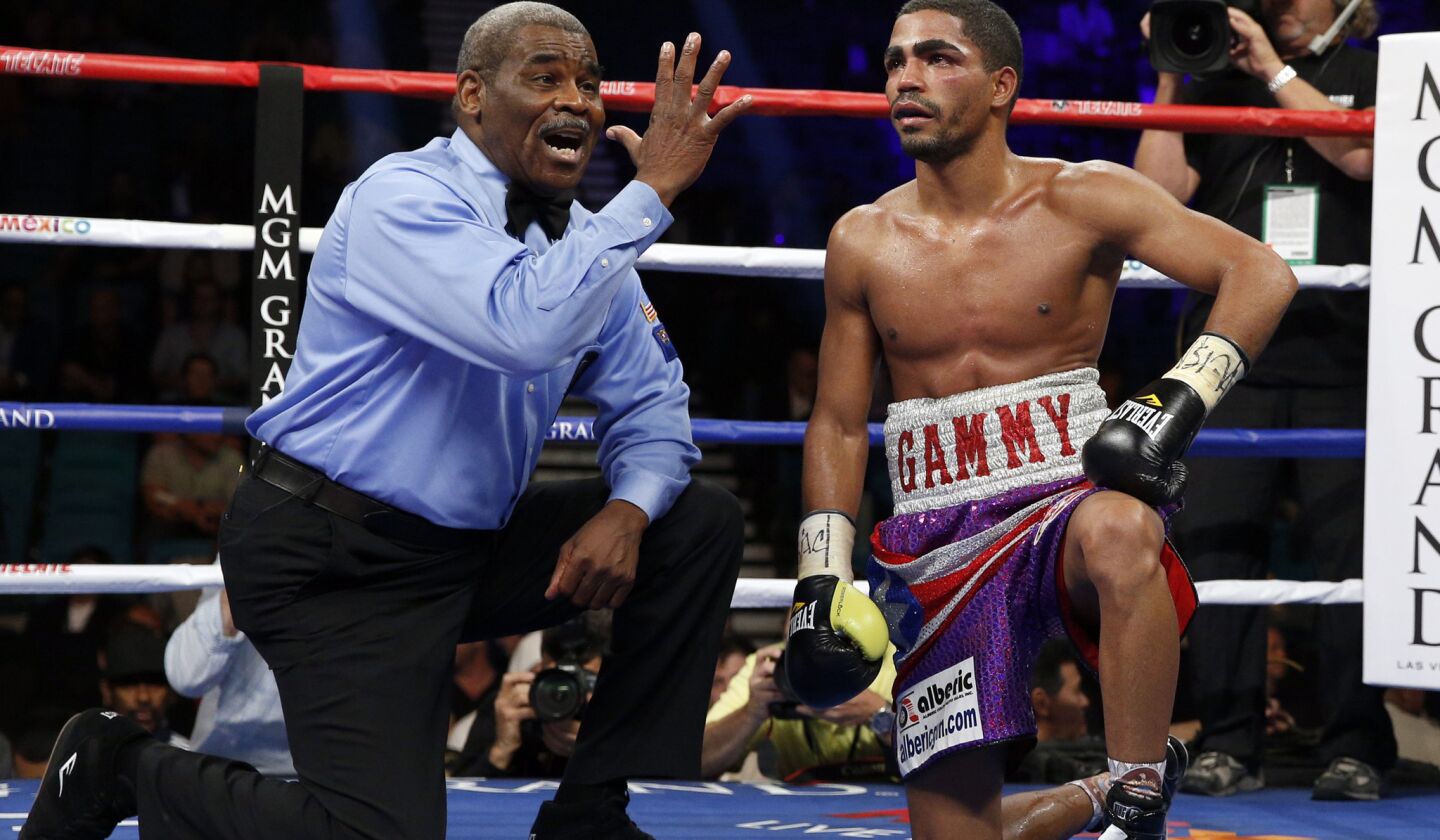 Gamalier Rodriguez gets a standing eight count from referee Robert Byrd after being knocked down by Vasyl Lomachenko during their featherweight title fight Saturday.