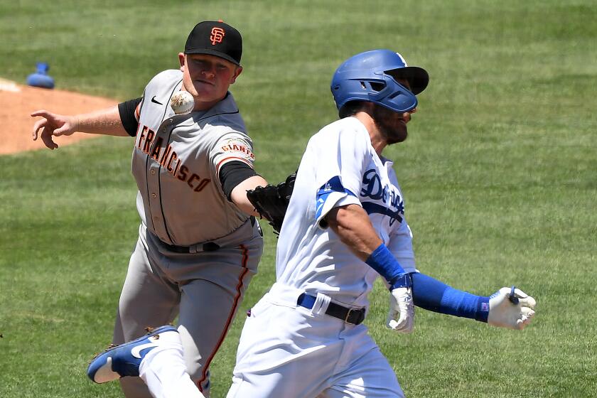 LOS ANGELES, CALIFORNIA JULY 25, 2020-Dodgers Cody Bellinger reaches 1st base on an infield single as Giants pitcher Logan Webb drops the the ball while trying to tag out Bellinger in the 1st inning at dodger Stadium Saturday. (Wally Skalij/Los Angeles Times)