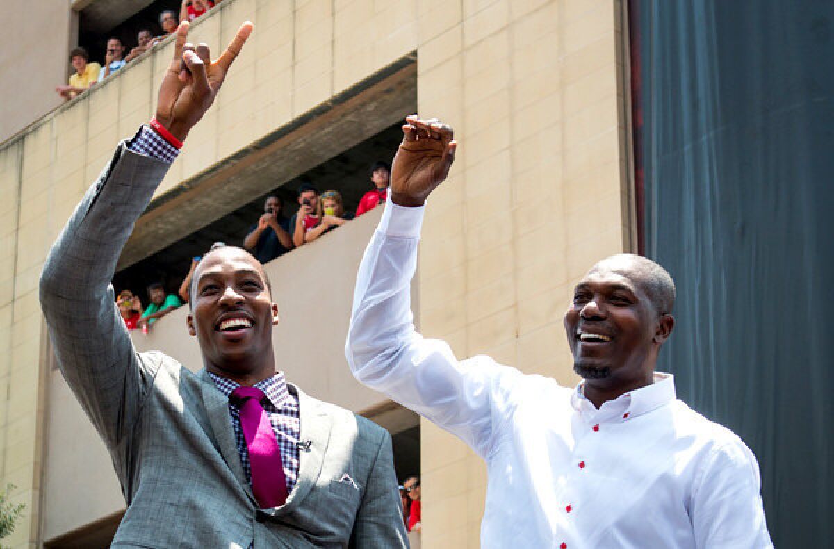 New Rockets center Dwight Howard, left, and Hall of Famer Hakeem Olajuwon wave to the crowd during an introductory rally outside of the Toyota Center in Houston on Saturday.