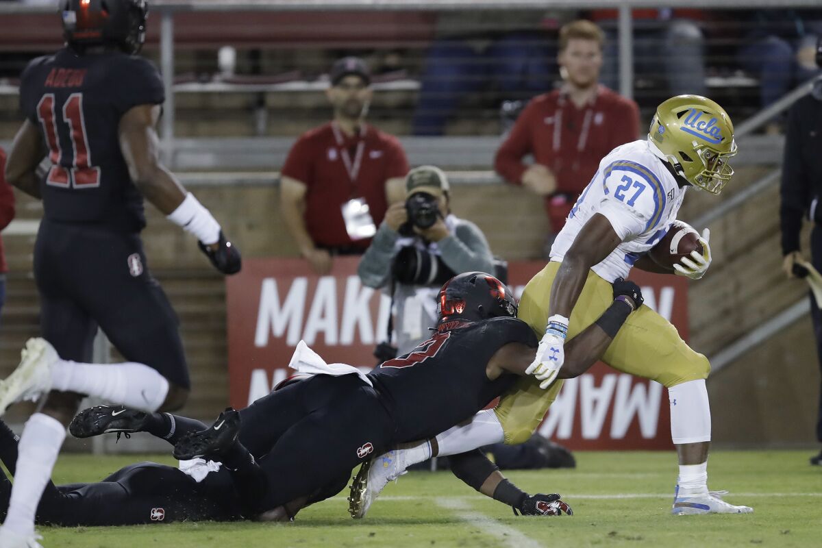 UCLA running back Joshua Kelley tries to break a tackle by Stanford's Malik Antoine.