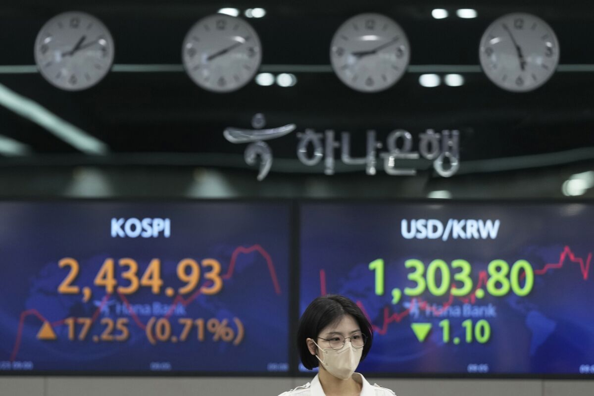 A currency trader walks near the screens showing the Korea Composite Stock Price Index (KOSPI), left, and the foreign exchange rate between U.S. dollar and South Korean won at a foreign exchange dealing room in Seoul, South Korea, Thursday, Feb. 23, 2023. Asian stock markets rose Thursday following Wall Street's biggest one-day decline in two months after notes from a Federal Reserve meeting showed officials expect to keep U.S. interest rates high to fight stubborn inflation. (AP Photo/Lee Jin-man)