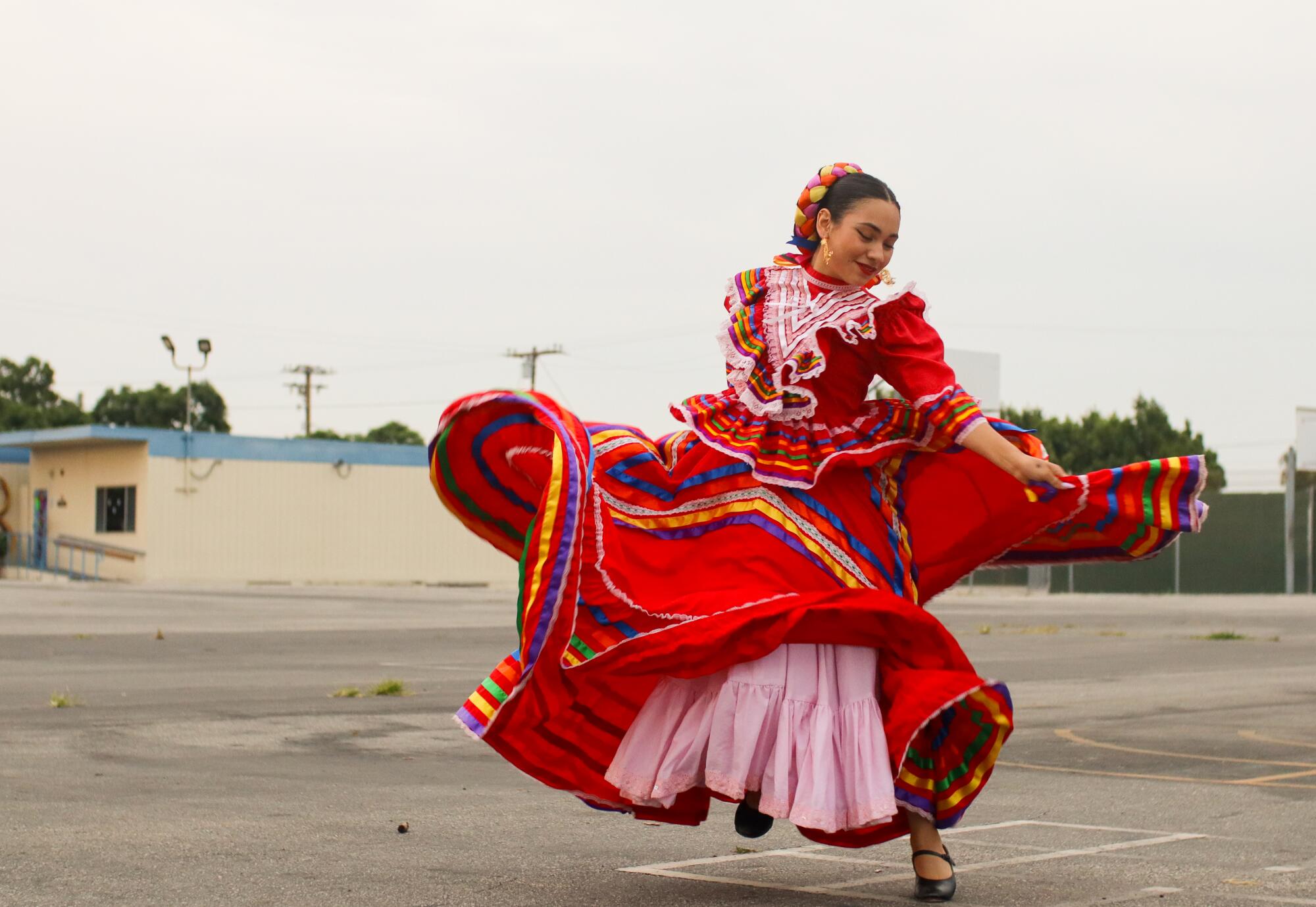 A woman dances folklorico at an elementary school.