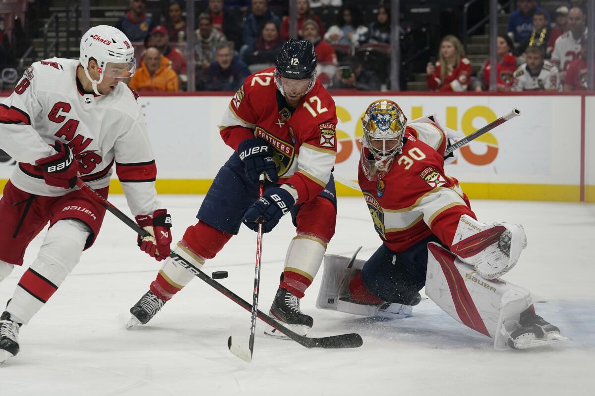 Carolina Hurricanes center Jack Drury (18) aims the puck as Florida Panthers center Eric Staal (12) and goaltender Spencer Knight (30) defend the net during the first period of an NHL hockey game, Wednesday, Nov. 9, 2022, in Sunrise, Fla. (AP Photo/Marta Lavandier)