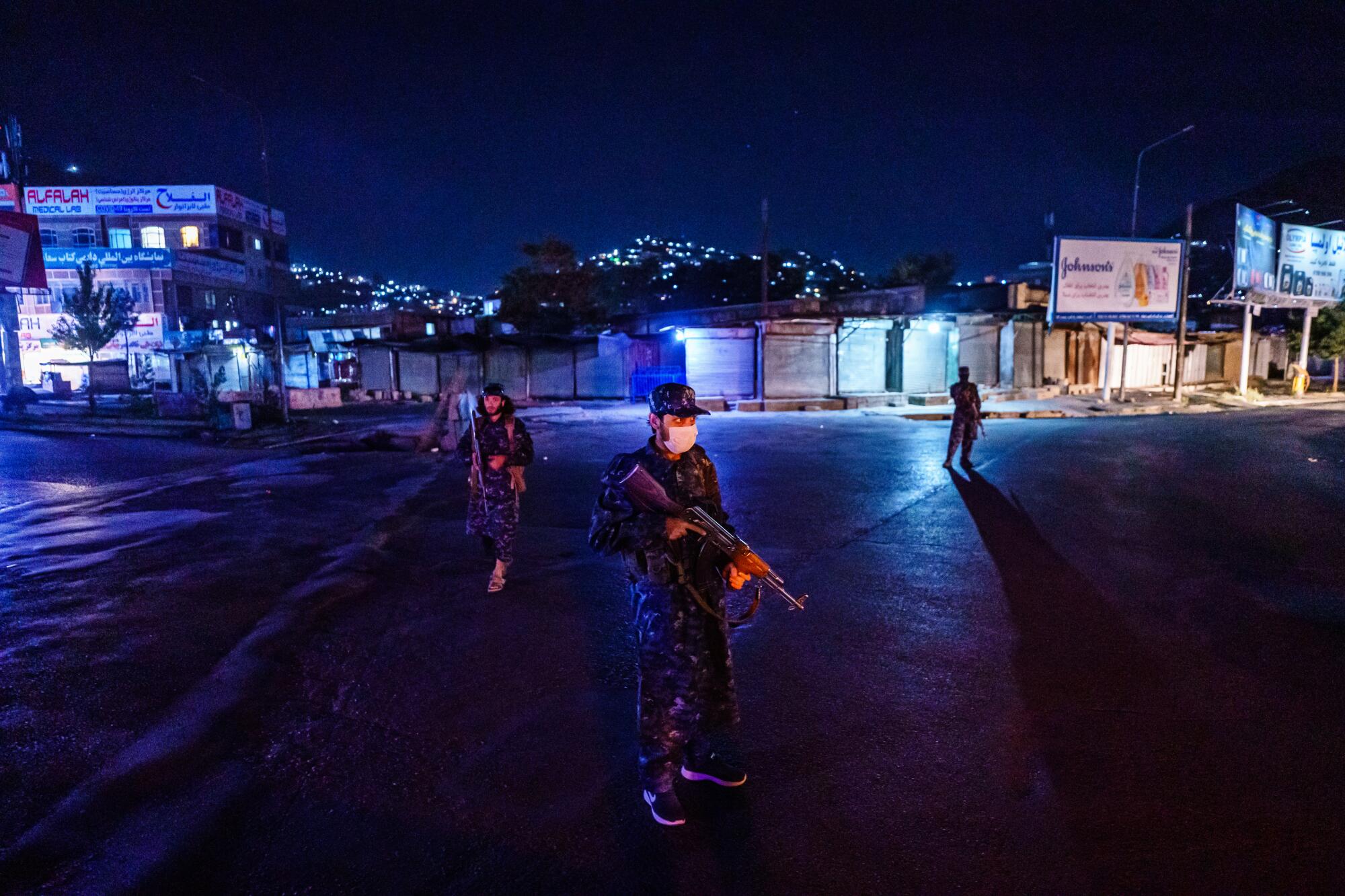 Taliban fighters in their new uniforms station themselves at a large traffic junction for a nightly security checkpoint.