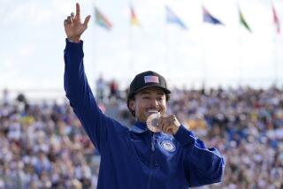 Nyjah Huston holds his bronze medal in front of his mouth while standing on the podium in Paris