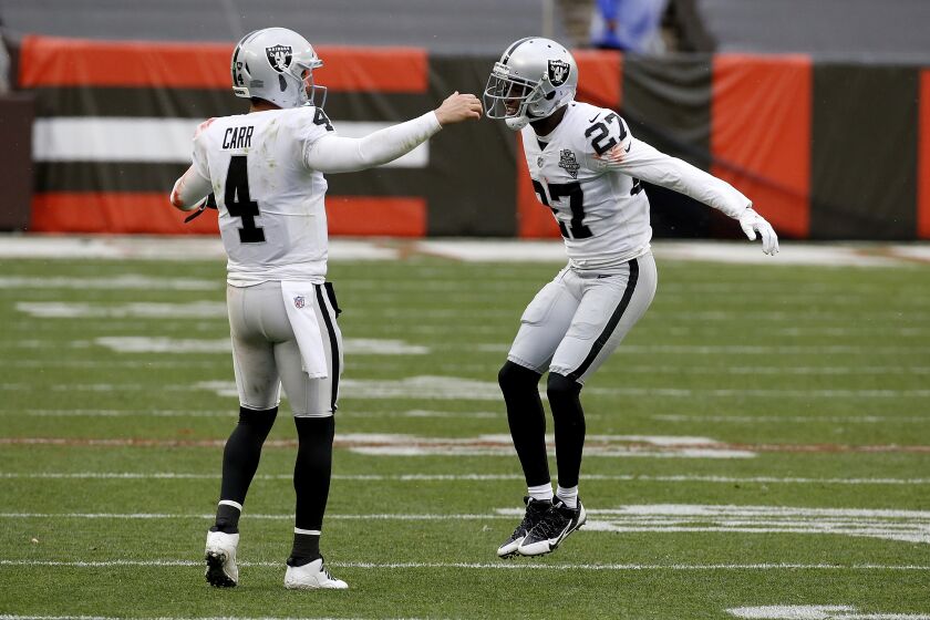 Las Vegas Raiders quarterback Derek Carr (4) congratulates cornerback Trayvon Mullen (27) after making a defensive stop during an NFL football game against the Cleveland Browns, Sunday, Nov. 1, 2020, in Cleveland. (AP Photo/Kirk Irwin)