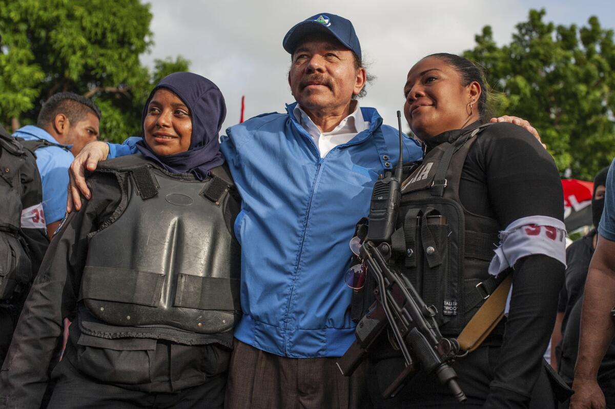 FILE - Nicaraguan police have their picture taken with President Daniel Ortega, in Masaya, Nicaragua, Friday, July 13, 2018. The government of the United States announced on Monday, June 13, 2022, that is restricting visas to members of the government of Nicaragua for having undermined democracy after the reelection of Ortega to the presidency. (AP Photo/Cristobal Venegas File)