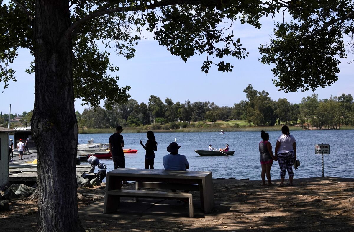 People stay in the shade as others row in a boat on Lake Murray. 