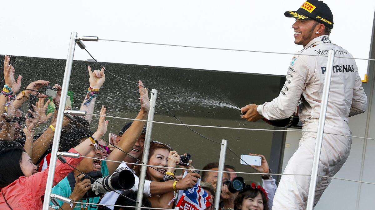 Formula One driver Lewis Hamilton celebrates on the podium after winning the Japanese Grand Prix on Sunday in Suzuka.