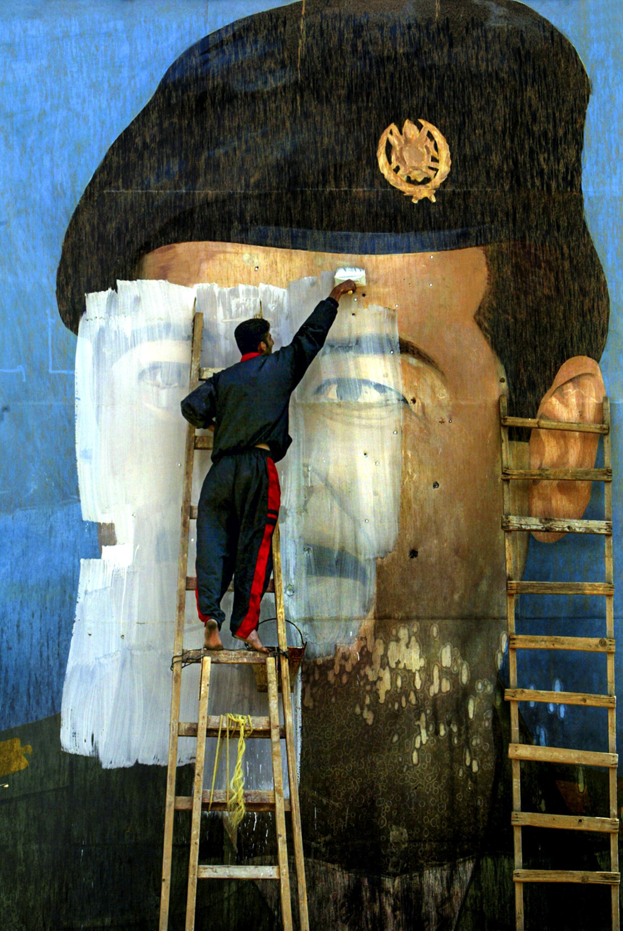 A mural of the face of Saddam Hussein is painted over by Salem Yuel at what was once a Fedayeen training camp in Baghdad.