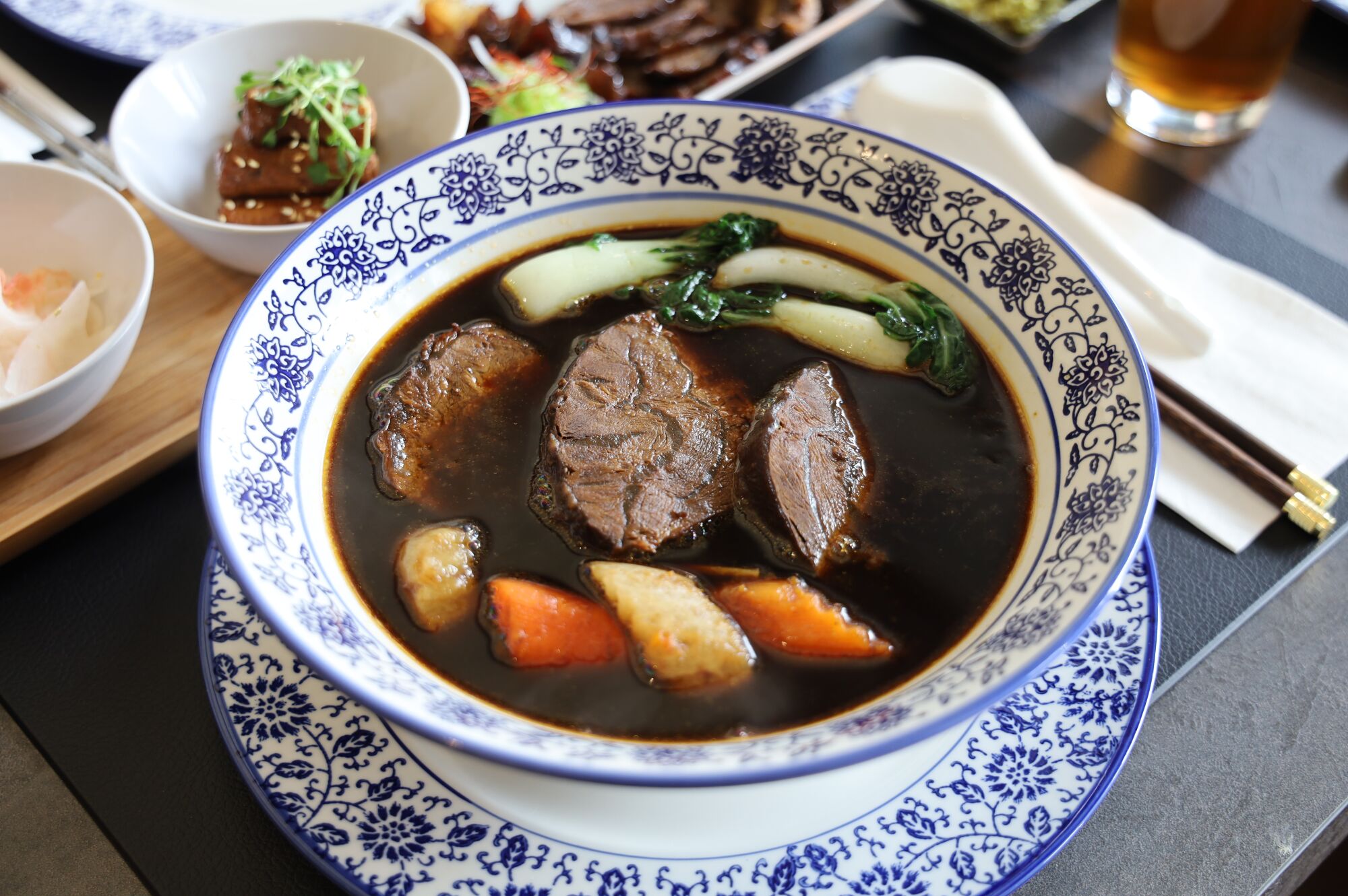 Une soupière bleue et blanche pleine de soupe de nouilles au bœuf braisé.