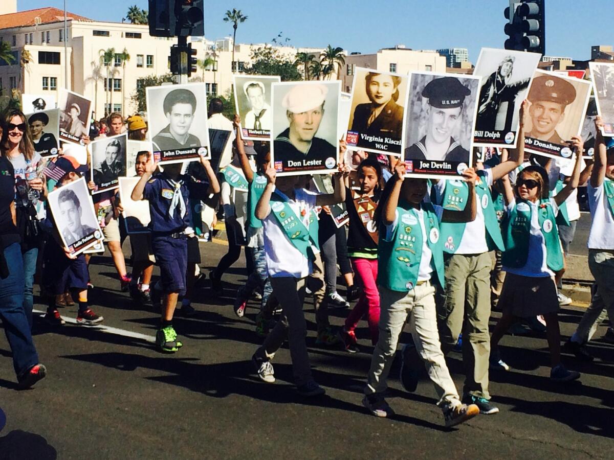 Children, including Girl Scouts, carried photos of World War II veterans as part of the Spirit of '45 entry in the 2015 San Diego Veterans Day parade.