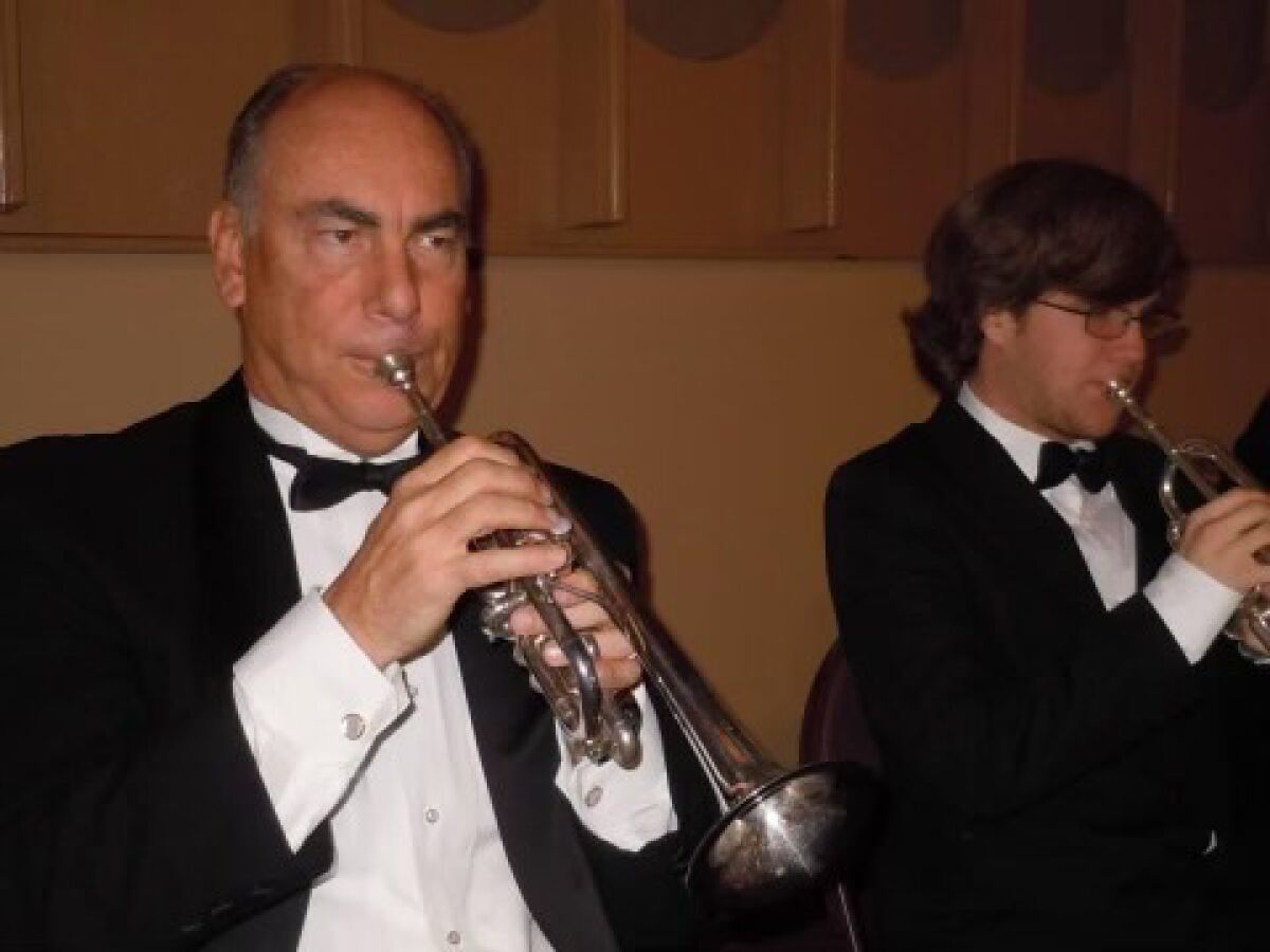 Two men, dressed in tuxedos and ties, play the trumpet. 