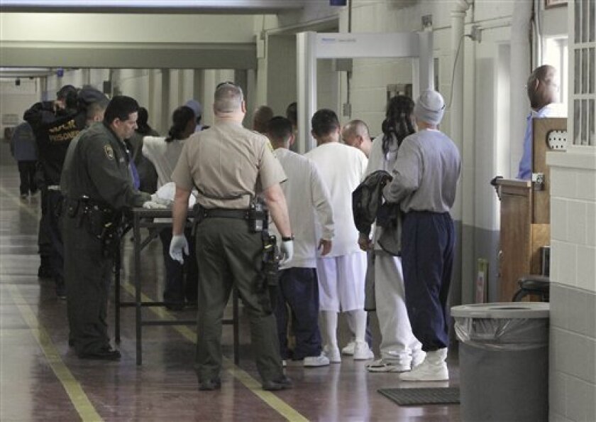 Inmates are screened for contraband after leaving the exercise yards at the Deuel Vocational Institute in Tracy, Calif. Friday March 2, 2012. California prisons marked a milestone Friday when California prison officials announced they have removed the last of nearly 20,000 extra beds that had been jammed into gymnasium and other common areas to house inmates who overflowed traditional prison cells.(AP Photo/Rich Pedroncelli)