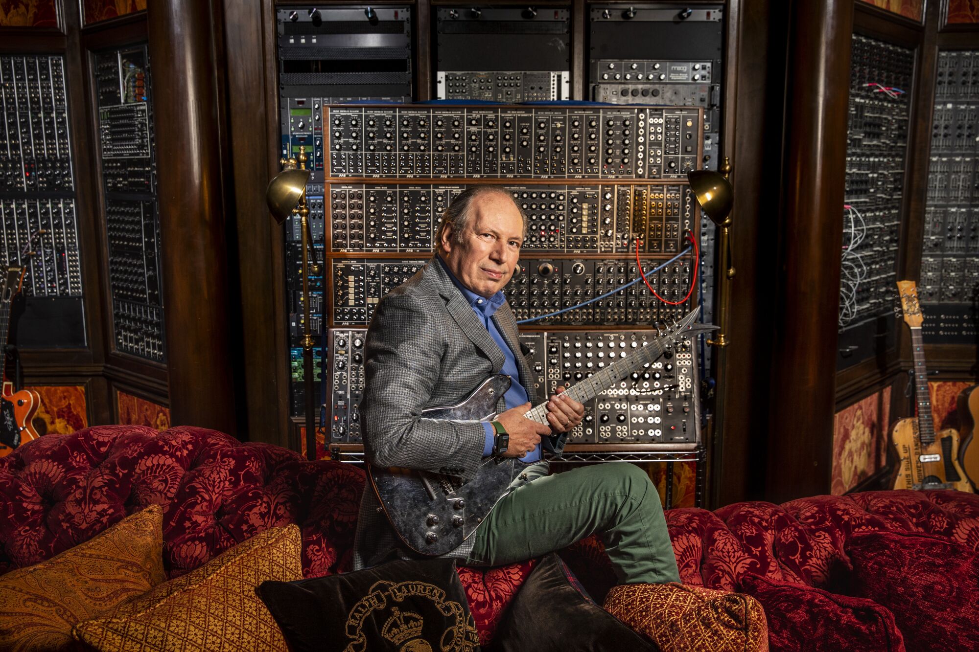 Composer Hans Zimmer strums a guitar in front of a synthesizer at his Remote Control Productions office.
