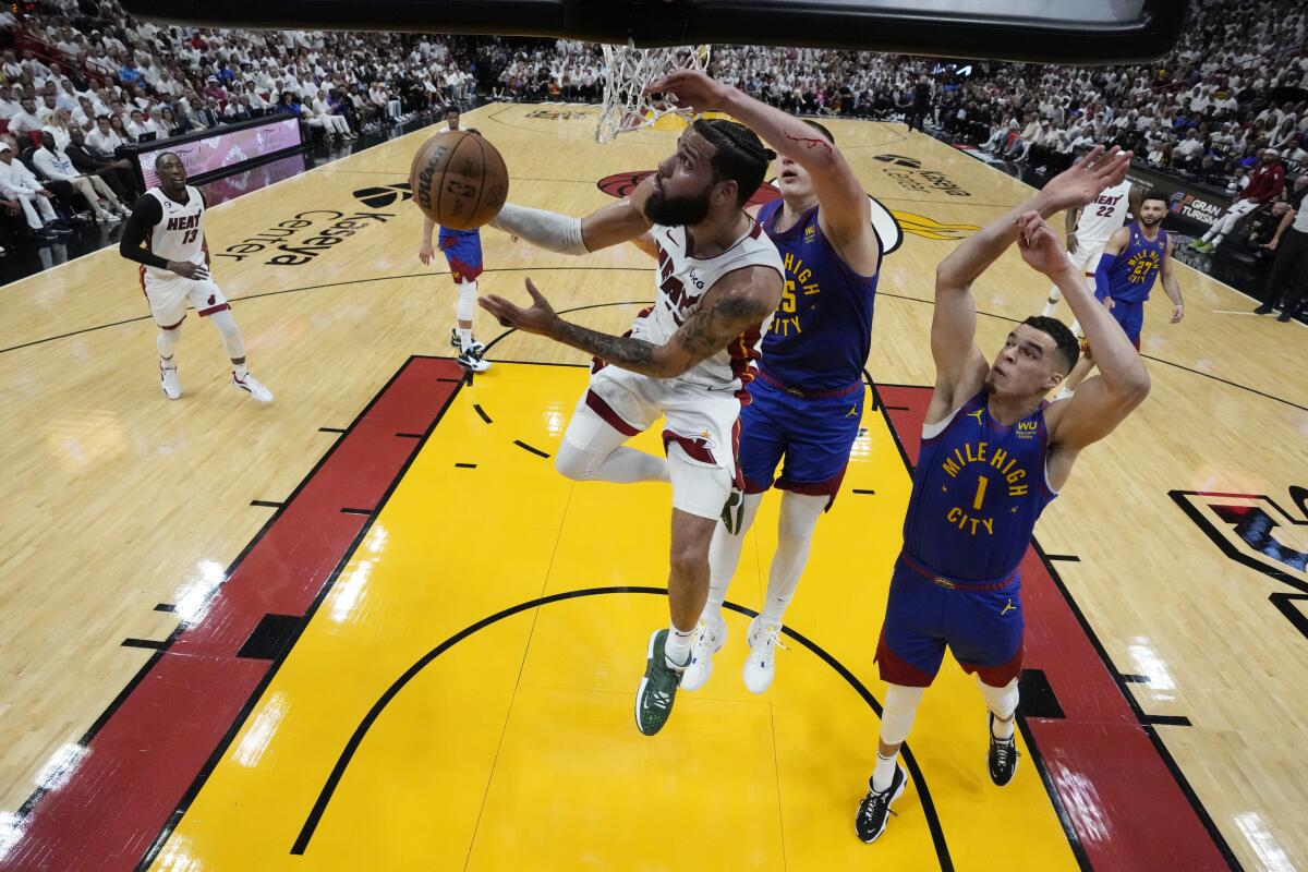 Miami Heat's Caleb Martin drives to the basket as Denver Nuggets' Nikola Jokic defends