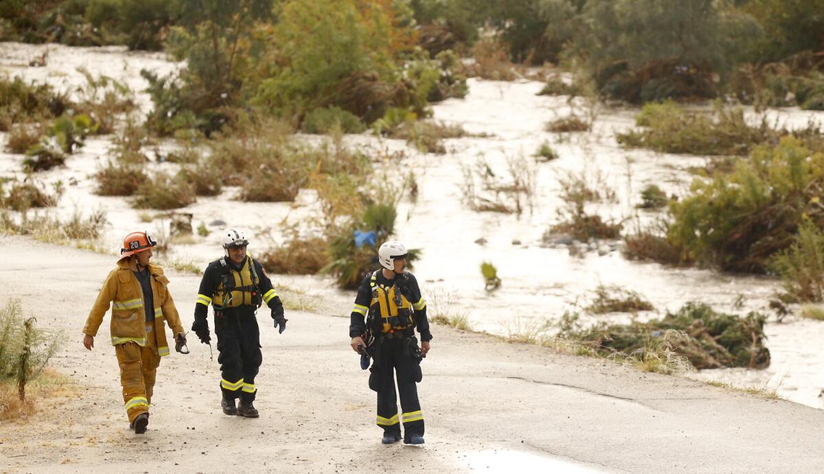 Los Angeles fire special op and swift water team members walk along the L.A. River at the Fletcher Drive bridge after rescuing someone from high water Tuesday morning.