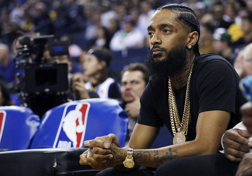 rapper Nipsey Hussle watches an NBA basketball game between the Golden State Warriors and the Milwaukee Bucks in Oakland