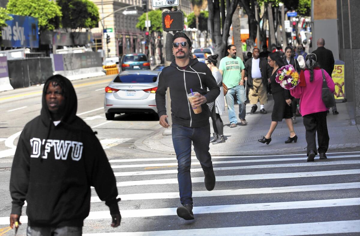 A pedestrian runs across the intersection at Hope and 2nd as the signal shows the red hand flashing.