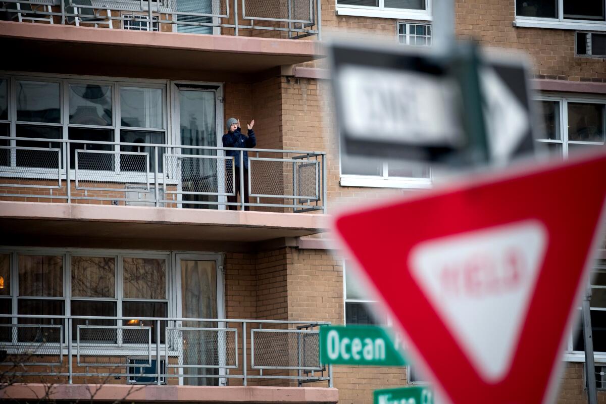 A resident applauds healthcare workers from the balcony of a Brooklyn building.