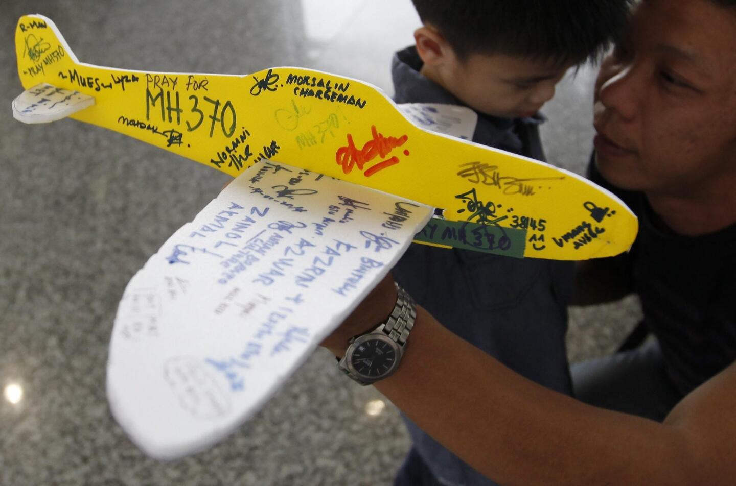 A man holds a model plane with well-wishing messages for the passengers of a missing Malaysian Airline plane at Kuala Lumpur International Airport, Malaysia, 15 March 2014.