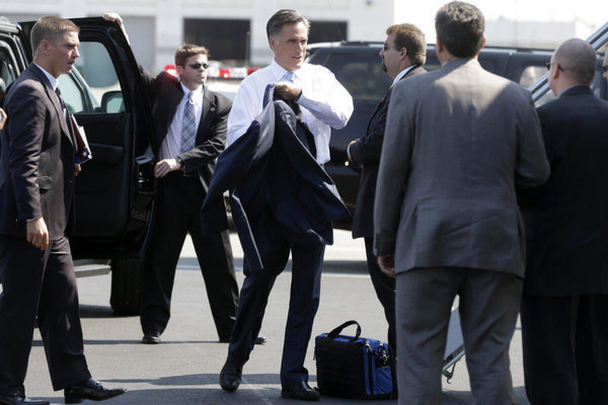 Mitt Romney puts on his jacket before boarding his campaign charter plane in Newark, N.J.