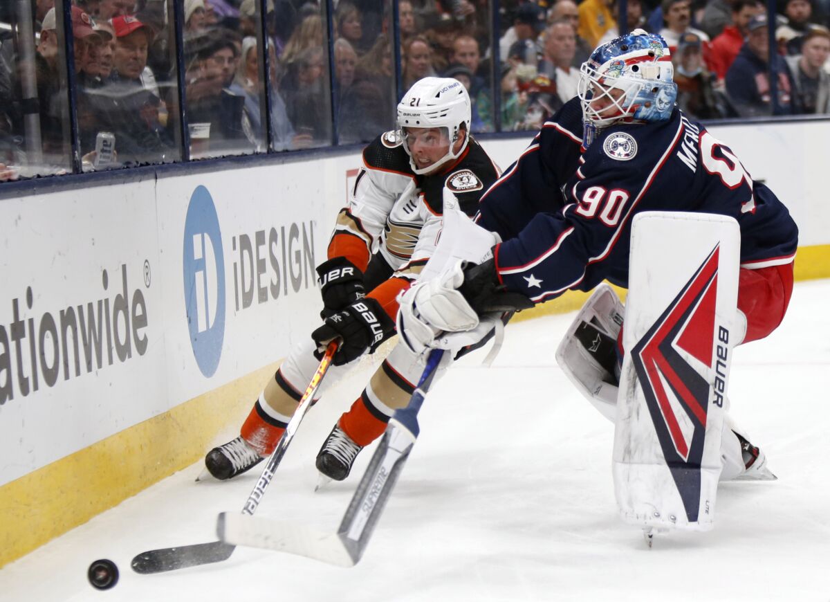 Ducks forward Isac Lundestrom reaches for the puck in front of Columbus Blue Jackets goalie Elvis Merzlikins.