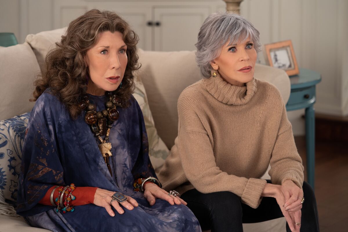 Two women sitting together on a couch looking stunned