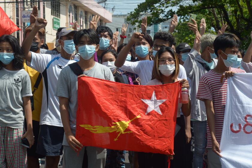 Anti-coup protesters hold the flag of the National League of Democracy party of ousted Myanmar leader Aung San Suu Kyi, while others flash the three-fingered salute during a "flash mob" rally in Bahan township in Yangon, Myanmar, Sunday, May 9, 2021. Myanmar's junta has labeled a shadow government of lawmakers and politicians ousted in a February coup and a people's defense force that is being set up to confront security forces as terrorist groups. (AP Photo)