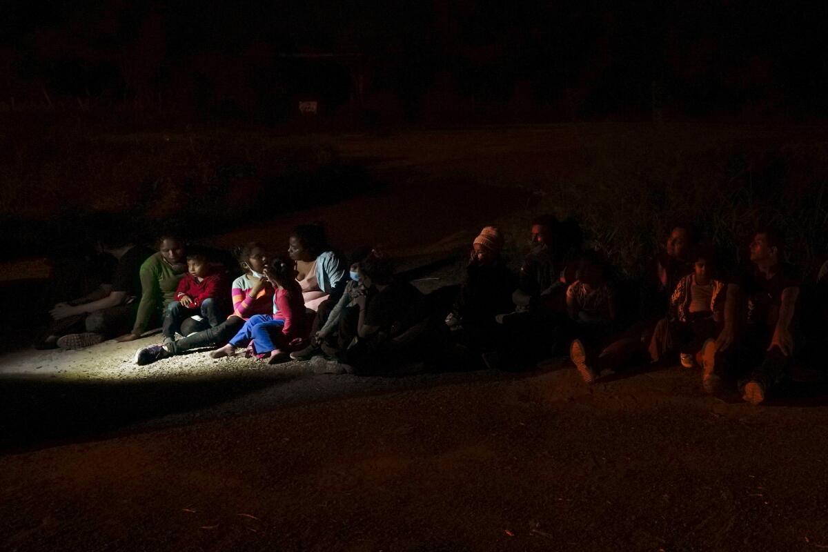 Migrants sitting on ground at U.S.-Mexico border