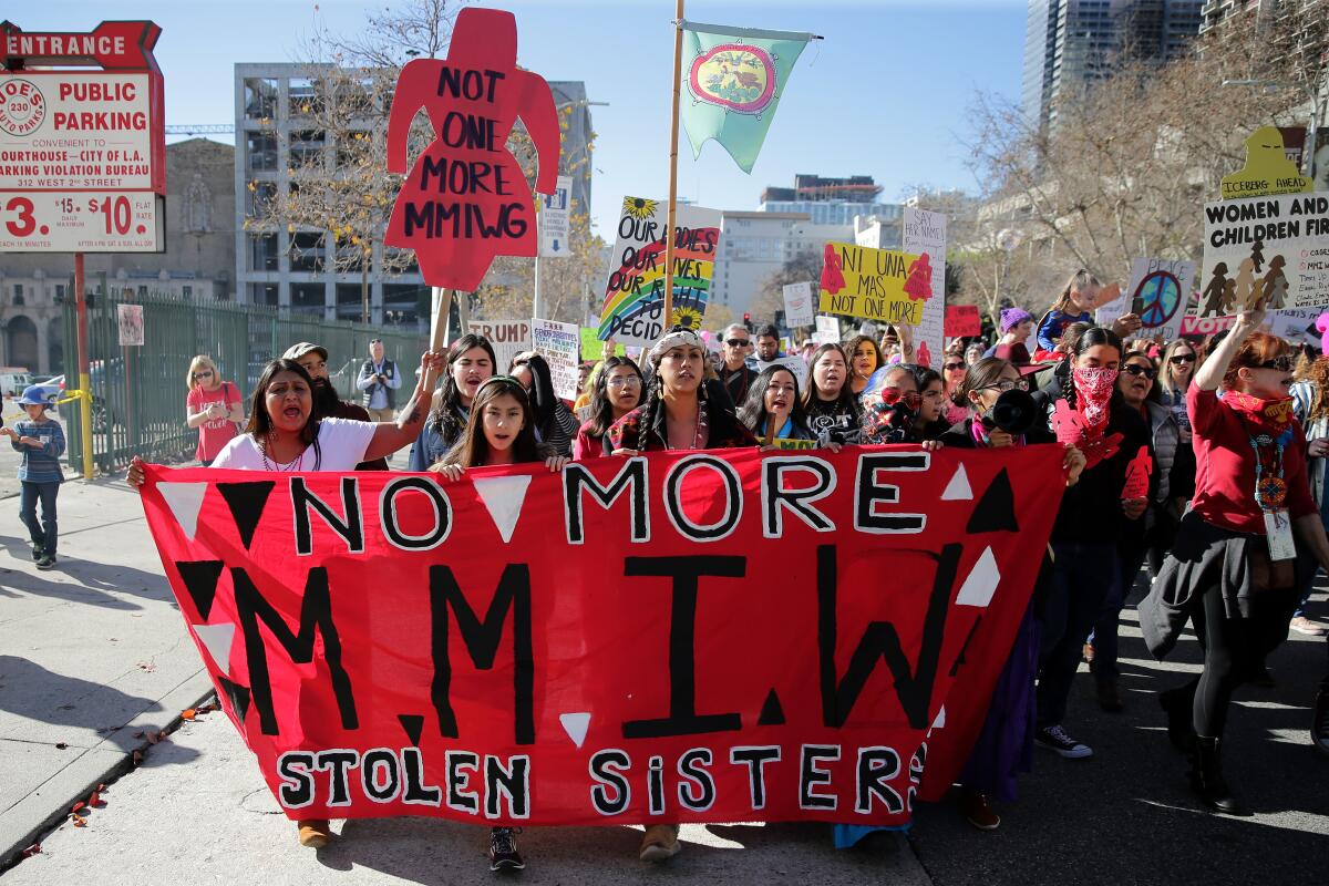 Activists march with banners and signs protesting violence against Indigenous women