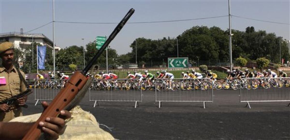 Participants ride pas guarding Indian policemen during the women's 112km cycling road race event in the Commonwealth Games in New Delhi, India, Sunday, Oct. 10, 2010. (AP Photo/Manish Swarup)