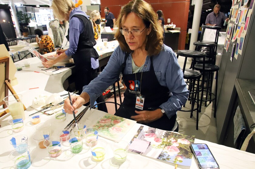 Mary Aslin, of San Juan Capistrano, paints tiles called "Delight of roses" at the Platter Painting Party.
