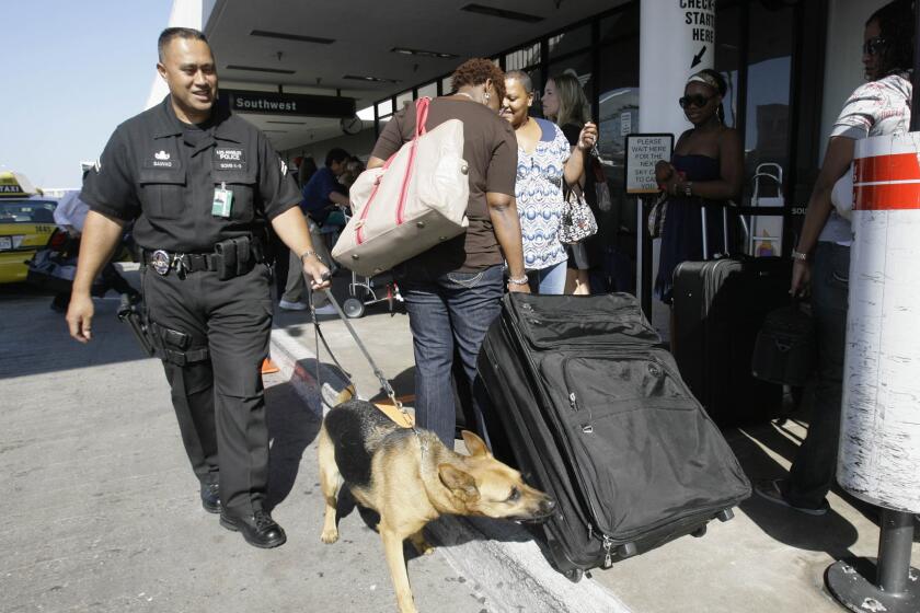 Los Angeles Police Officer Mark Sauvao and his K-9 partner Aya patrol a baggage check-in line Friday, Aug. 31, 2007, at Los Angeles International Airport, at the start of Labor Day holiday weekend in Los Angeles. (AP Photo/Nick Ut)