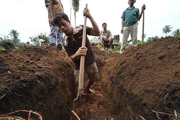 Nasirwan, 26, digs a grave for his father, a victim of a Sept. 30 quake at Lubuk Laweh village. Indonesia called off the search for survivors in the city of Padang as officials sought to contain the risk of disease caused by thousands of trapped bodies.