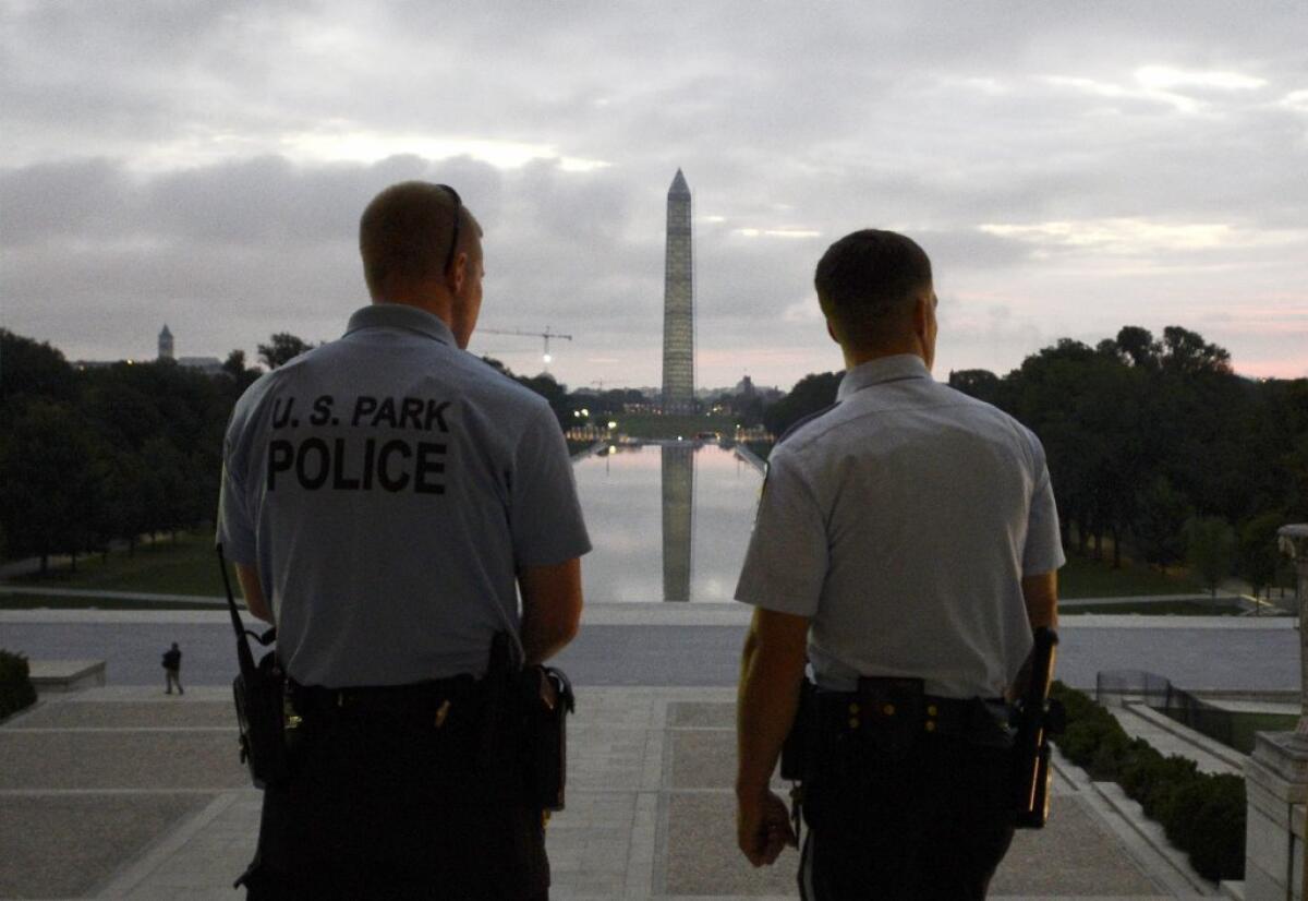 U.S. Park Police look out at dawn Thursday from the top of the steps of the Lincoln Memorial, now reopened to the public, facing the Washington Monument.
