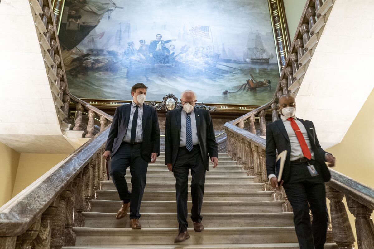 Sen. Bernie Sanders and others walking down a broad staircase at the Capitol