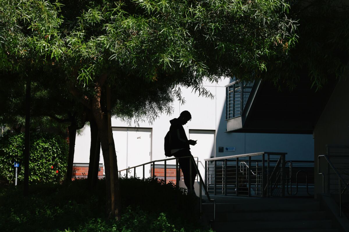 A student checks his phone between classes at East Los Angeles College in Los Angeles.