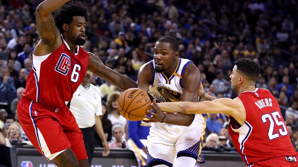 Warriors forward Kevin Durant tries to split the defense of Clippers center DeAndre Jordan and guard Austin Rivers during their preseason game Tuesday night in Oakland.