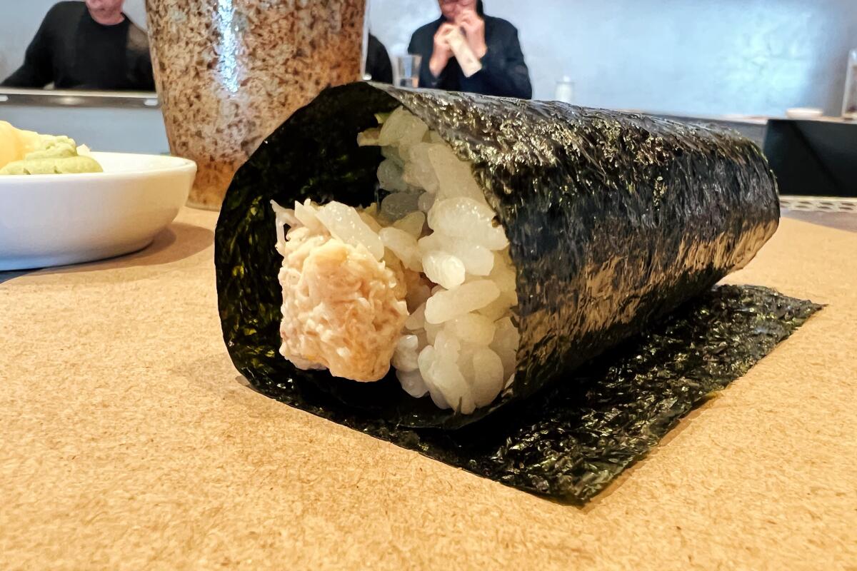 A hand roll at KazuNori, with rice and fish visible inside the seaweed wrapper
