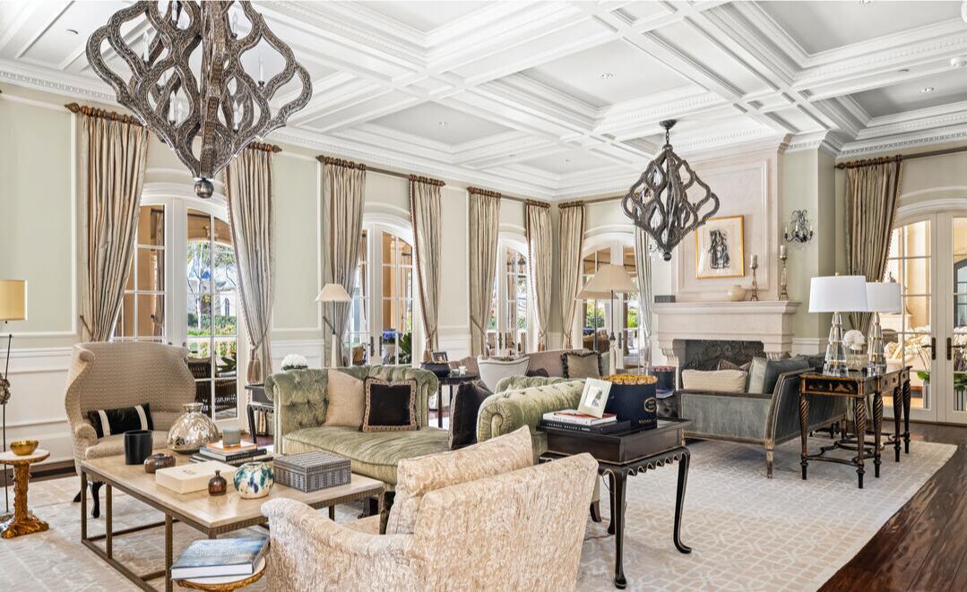 The living room with furnishings, light fixtures, windows and a light-colored rug.