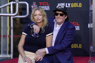 Actor Michael Madsen, right, poses with his wife DeAnna Madsen while crouching on a red carpet