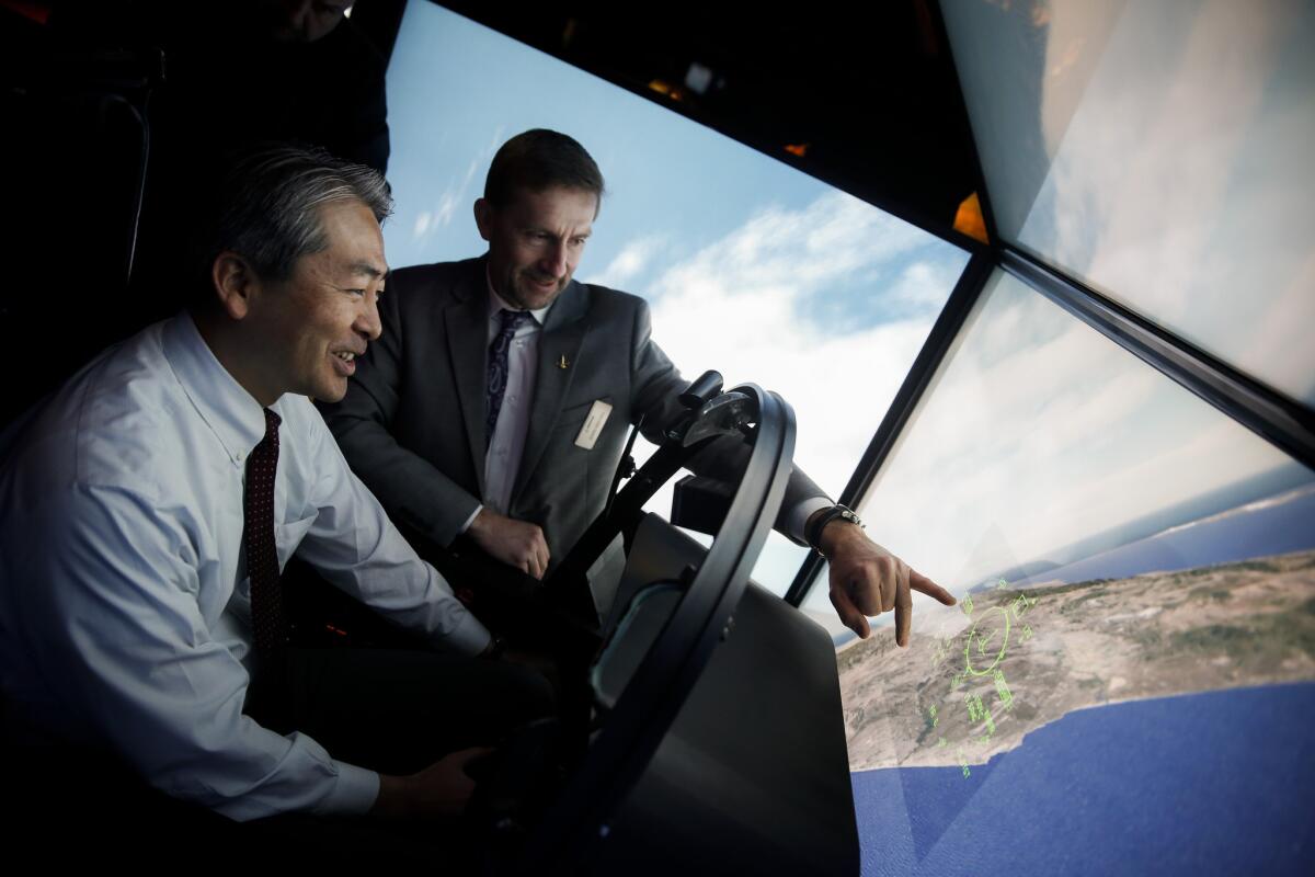 California Assemblyman Al Muratsuchi, left, receives flying instructions from John Keeven, manager, naval programs flight simulation for Boeing, inside an FA-18 Super Hornet flight simulator, following a rally in support of the Torrance manufacturers Boeing and Moog sustaining Super Hornet and Growler production, outside the Moog headquarters in March. Muratsuchi is locked in a tight reelection campaign against GOP challenger David Hadley.