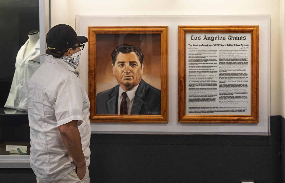 A person looks at a framed painting of a man next to a newspaper article