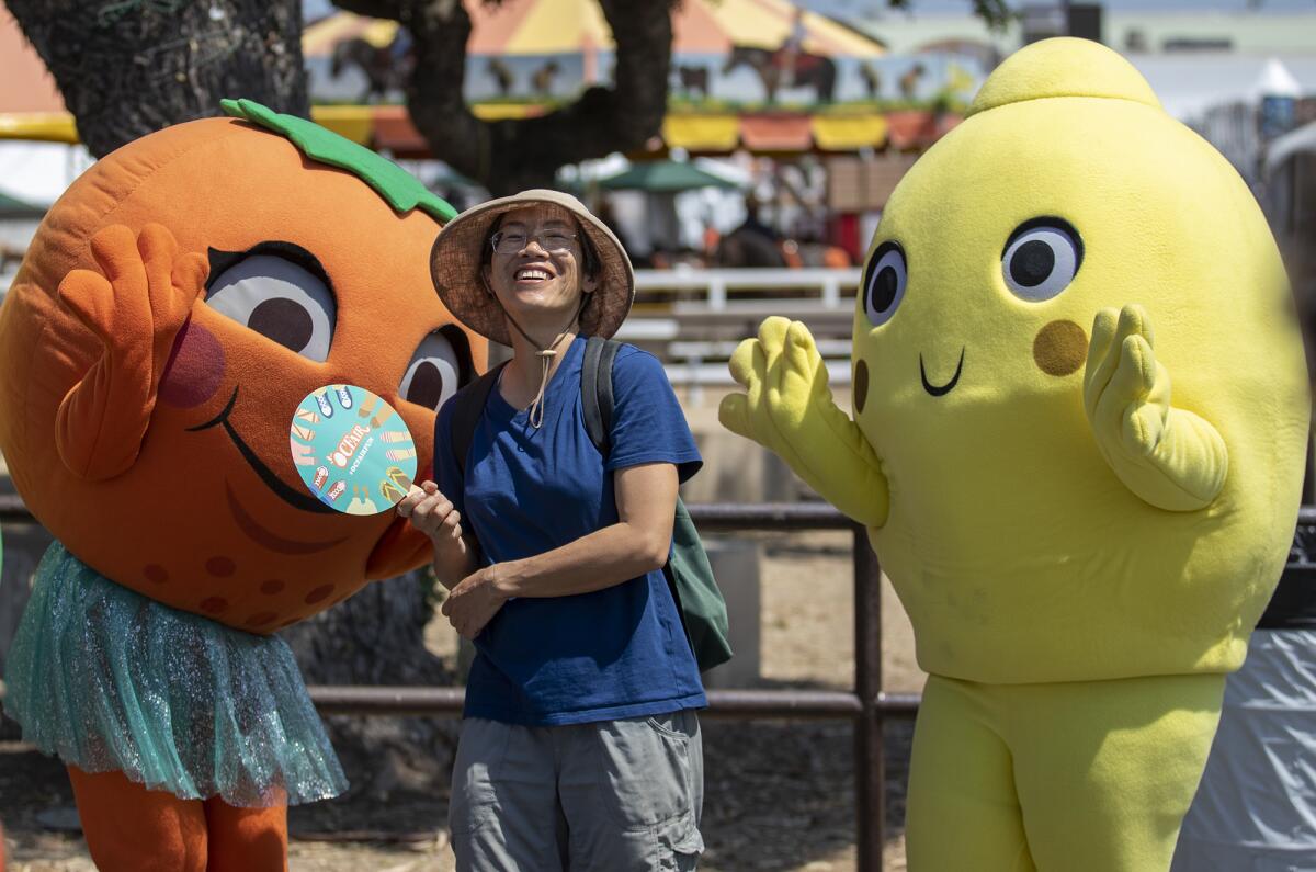 Lydia Lee, of San Francisco, poses with Olivia the Orange and Sunny the Lemon Friday on the opening day of the O.C. Fair. 