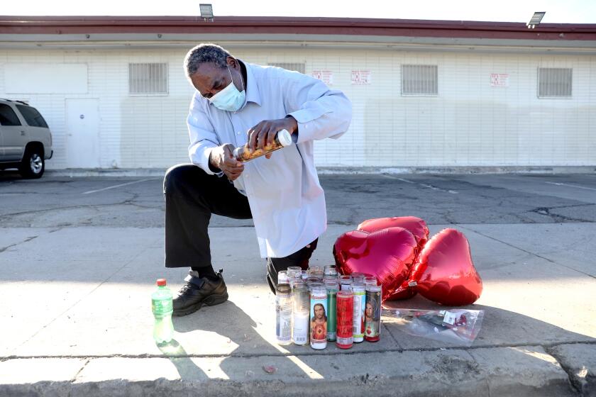 COMPTON, CA - OCTOBER 26: Raymond Sanders, 66, of Compton, lights candles at a memorial for his uncle Rev. Reginald Moore on Tuesday, Oct. 26, 2021 in Compton, CA. Rev. Reginald Moore, 67, was fatally shot in the chest outside The Upper Room church where he just led a Bible study lesson. The shooting happened Sunday about 11:50 a.m. in the 1000 block of Compton Boulevard, the LASD reported. (Gary Coronado / Los Angeles Times)