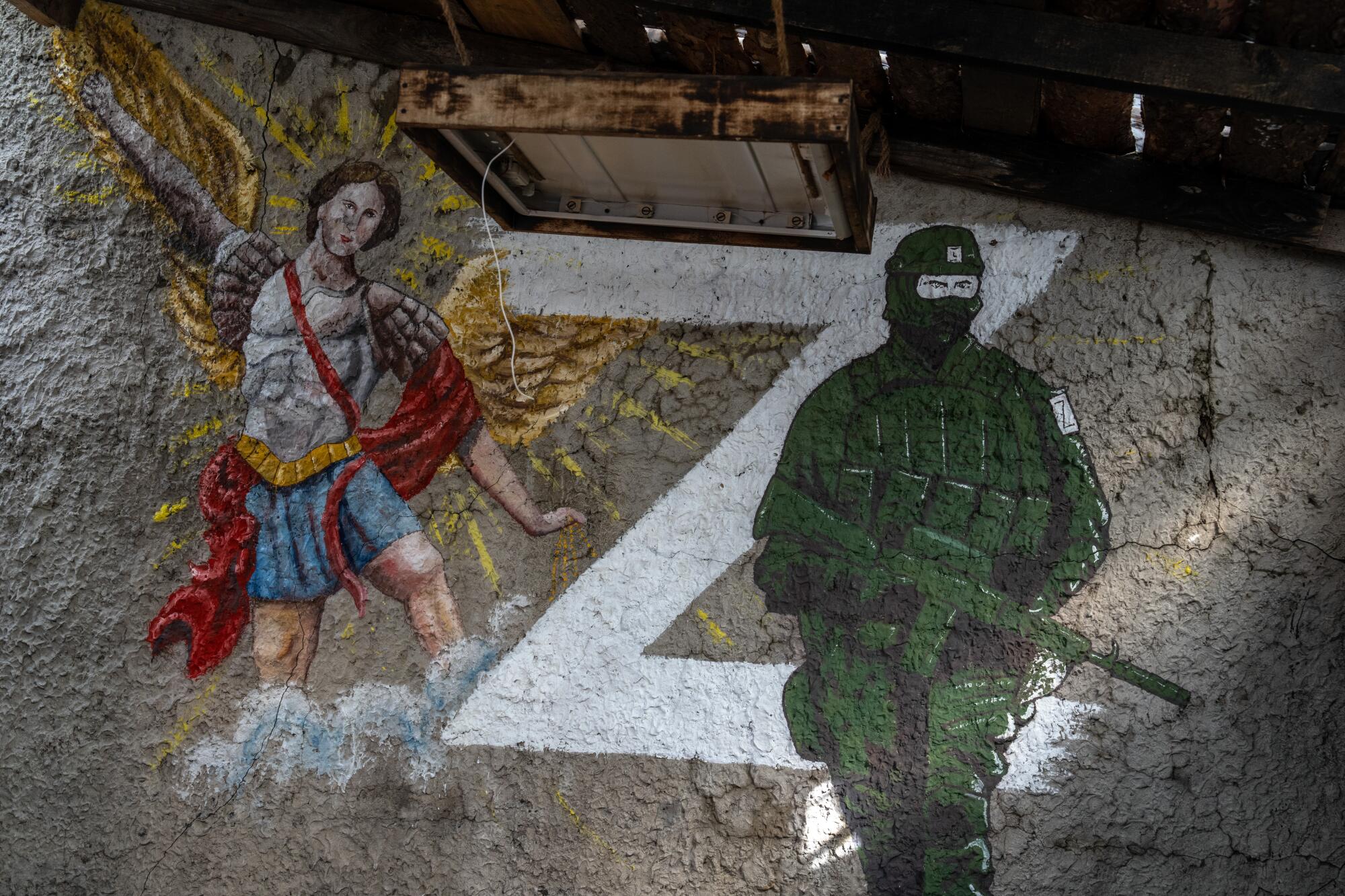 A picture of a Russian soldier next to the "Z" military symbol and St. Michael the Archangel painted on a wall  