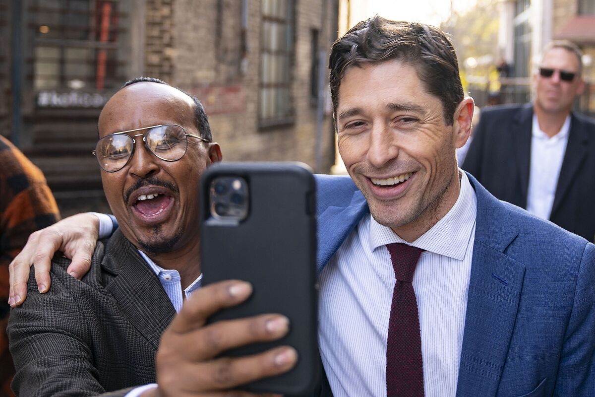 Kadir Abdulle takes a selfie photo with incumbent Minneapolis Mayor Jacob Frey as they walked back to the campaign office after holding his first news conference since being declared the winner of the 2021 election Wednesday, Nov. 3, 2021 outside Loring Corners in Minneapolis. Abdulle ran the Somali canvass for Mayo Jacob Frey's campaign. (Alex Kormann/Star Tribune via AP)